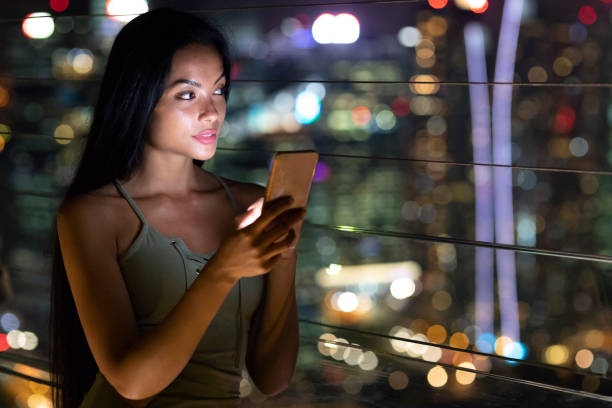 istock Smiling woman text messaging outdoors, at night 1057550076