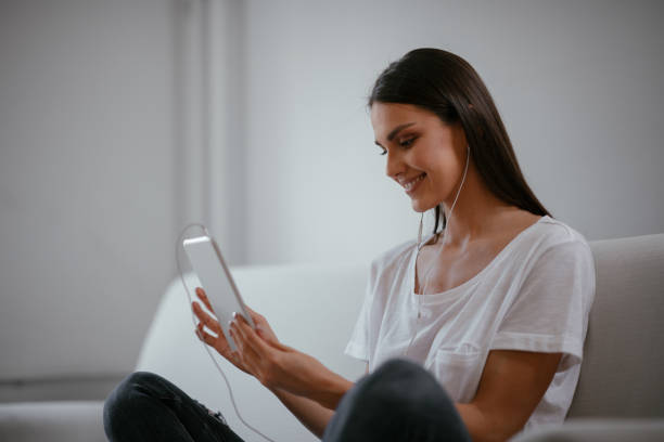 istock Young female using tablet in her living room 1057552030