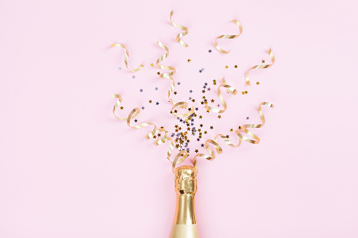 Botella de Champagne con estrellas de confeti y serpentinas de la fiesta en fondo rosa. Navidad, cumpleaños o boda concepto. La endecha plana. photo