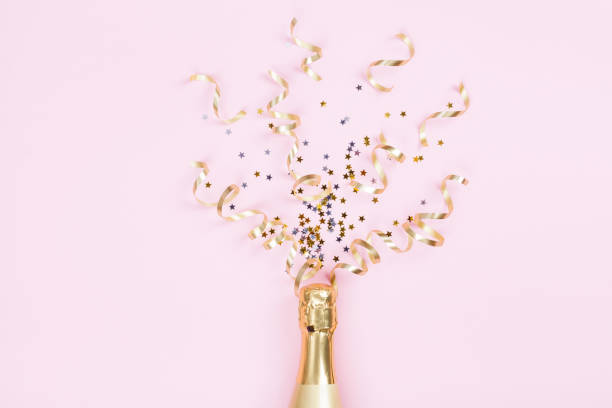 champagne bottle with confetti stars and party streamers on pink background. christmas, birthday or wedding concept. flat lay. - pink champagne fotos imagens e fotografias de stock