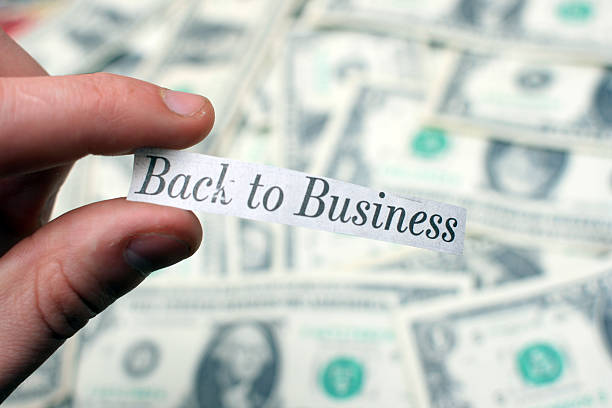 "Back to Business" - Positive Newspaper Headline Against Dollar Bills A concept photograph representing an economic rebound/overcoming adversity. reopening photos stock pictures, royalty-free photos & images