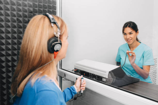 audiologist doing hearing test in special audio room audiologist doing hearing exam to a mature patient using audiometer in special audio room. audiologist stock pictures, royalty-free photos & images