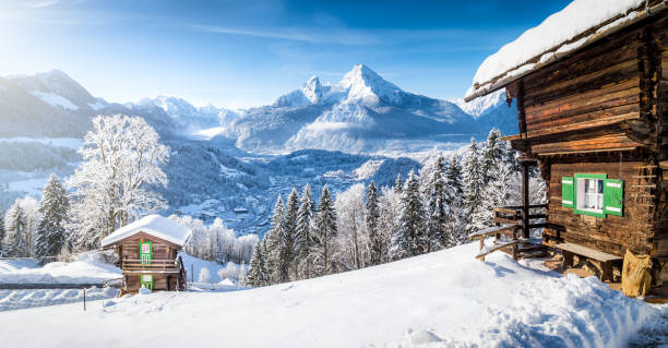 Winter wonderland with mountain chalets in the Alps Panoramic view of beautiful winter wonderland mountain scenery in the Alps with traditional mountain chalets on a cold sunny day with blue sky and clouds tyrol state austria stock pictures, royalty-free photos & images