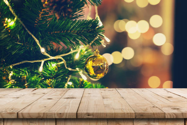 istock Empty wood table and christmas pine cones hanging from Christmas tree with display montage for product. 1057574860