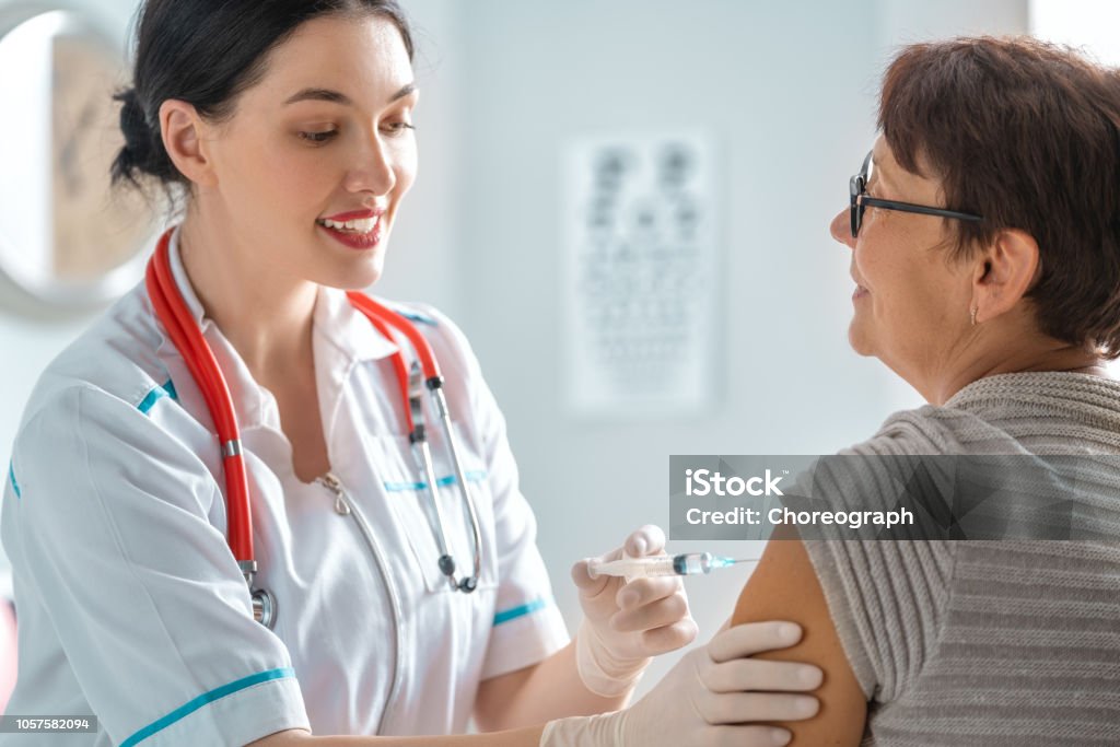 Doctor vaccinating a woman Doctor vaccinating a woman in the clinic. Vaccination Stock Photo