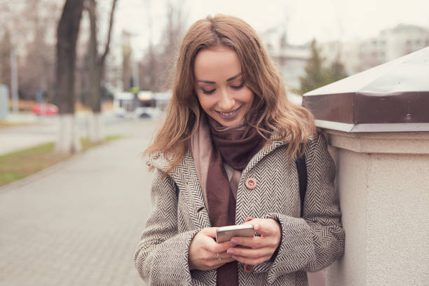 istock Cheerful woman using phone outdoors 1057584848