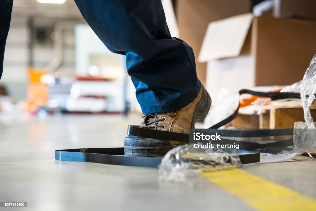 Un tema de seguridad industrial.  Un trabajador de tropezar con una papelera en una fábrica - Foto de stock de Caer libre de derechos