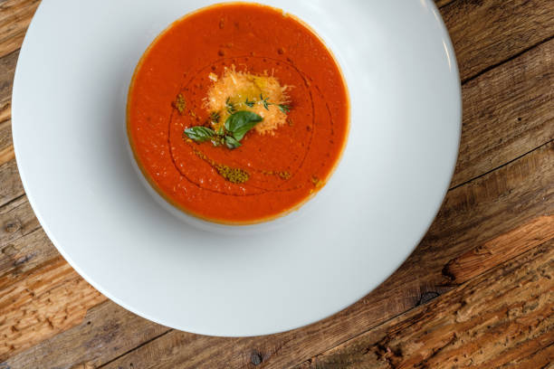 istock Vegetable tomato soup with cheese and green herbs on rustic wooden background. Top view 1057597198