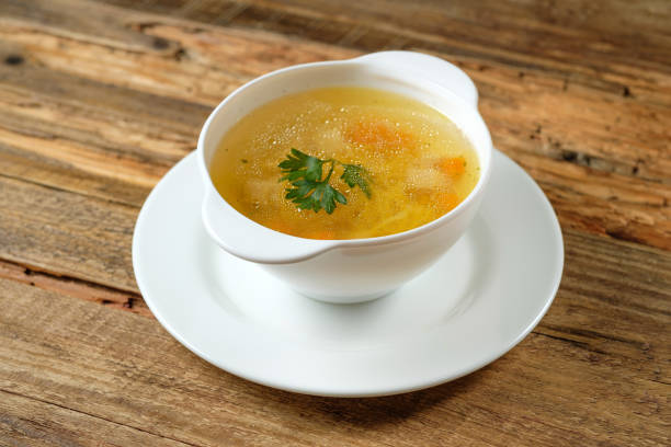 brodo - zuppa di pollo con noodles in una ciotola bianca su sfondo legno in stile rustico - brodo foto e immagini stock