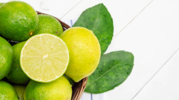 istock Green lime in a basket on a white wooden table. 1057599860
