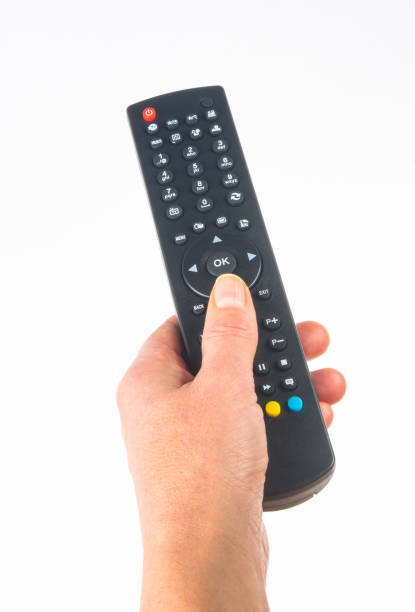 istock hand holding a remote control on white background, close-up 1057607346