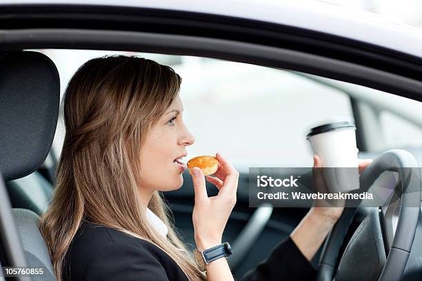 Charming Businesswoman Eating And Holding A Drinking Cup While Driving Stock Photo - Download Image Now