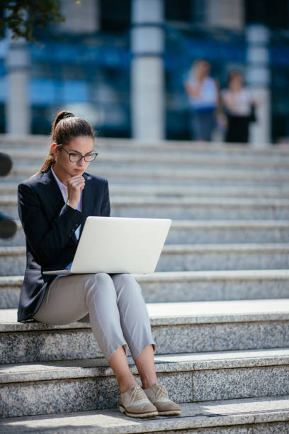 istock Beautiful young woman using laptop outdoors 1057609846