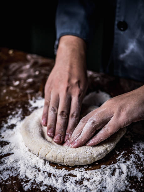 istock pastry chef hand kneading Raw Dough with sprinkling white flour over kitchen table. 1057612576