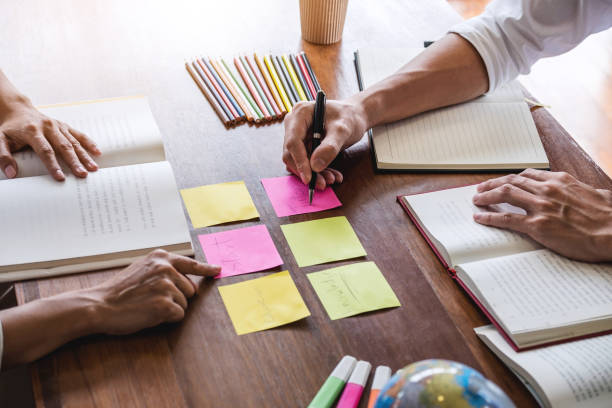 istock High school or college student group sitting at desk in library studying and reading, doing homework and lesson practice preparing exam to entrance, education concept 1057613522