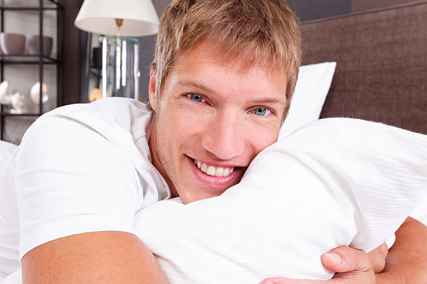 handsome man on pillow smiling at camera stock photo