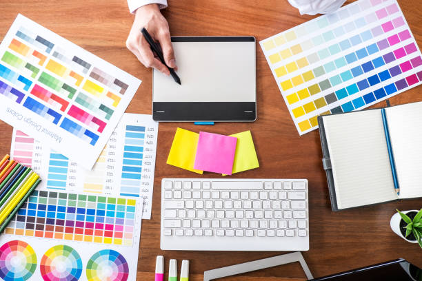 istock Image of male creative graphic designer working on color selection and drawing on graphics tablet at workplace with work tools and accessories, top view 1057614760