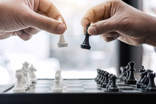 Businessman's hand playing chess game to development analysis new strategy plan, business strategy leader and teamwork concept for win and success.
