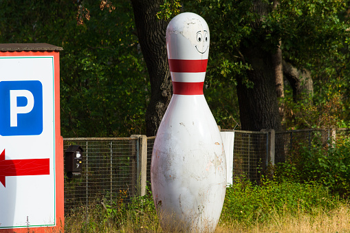 Bowling cone with white and red stripes in front of green background
