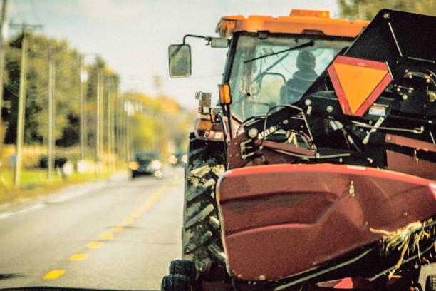 Make way, tractor on the road On a country road in Quebec, a tractor is driving. Image with color treatment to accentuate the idea of yesteryear. agricultural equipment stock pictures, royalty-free photos & images