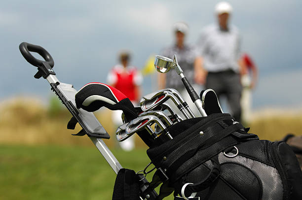 Close-up of golf bag with clubs with golfers blurred in back stock photo