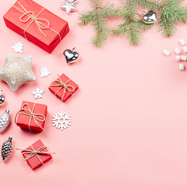 istock Christmas background with fir branches, lights, red giftboxes, pink decorations, hot drink with marshmallows on pink 1057634454