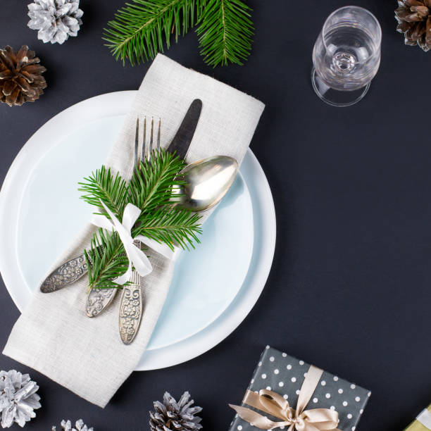 istock Christmas table setting with plates, silverware, gift box and decorations in black and gold colors 1057634542