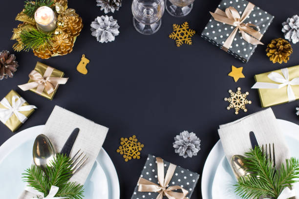 istock Christmas table setting with plates, silverware, gift box and decorations in black and gold colors 1057634548