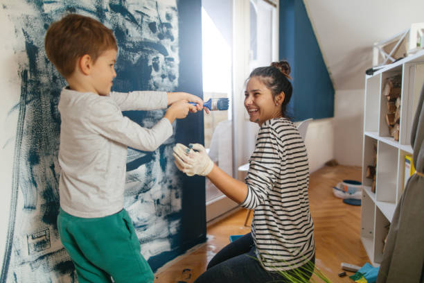 Its a paint fight Mother and son working together on repainting a wall in their living room council flat stock pictures, royalty-free photos & images