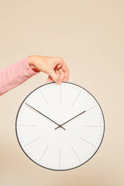 istock Woman hand hold wall clock on a white background 1057649808