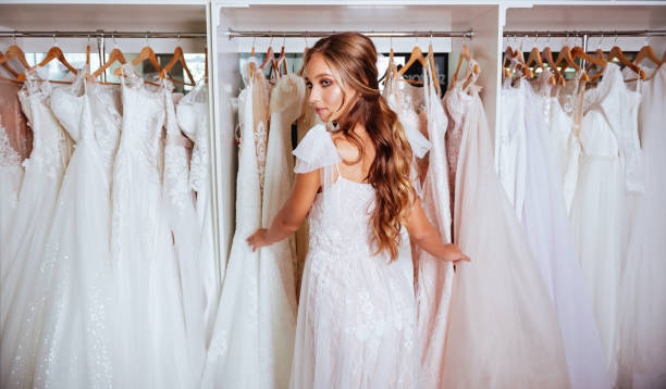 istock Attractive young bride is smiling while choosing wedding dress 1057654040