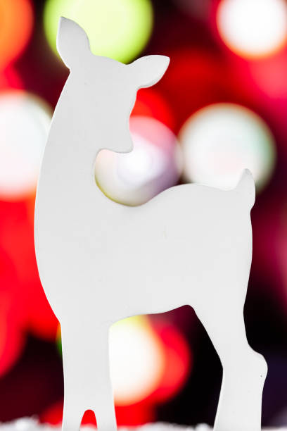 istock White wooden deer with a Christmas lights background 1057663106