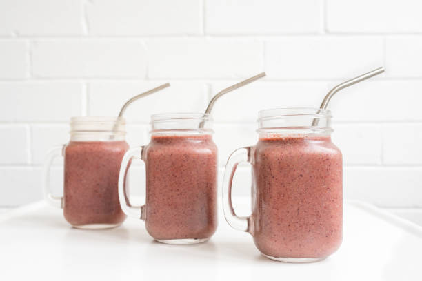 istock Three berry smoothies in glass mugs with metal straws 1057673352