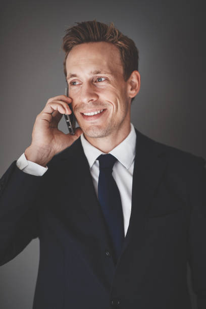 istock Smiling businessman talking on his cellphone against a gray background 1057683800