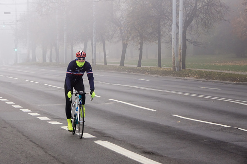 Vilnius, Lithuania - October 21, 2018: Cyclist passing empty city street on foggy morning.