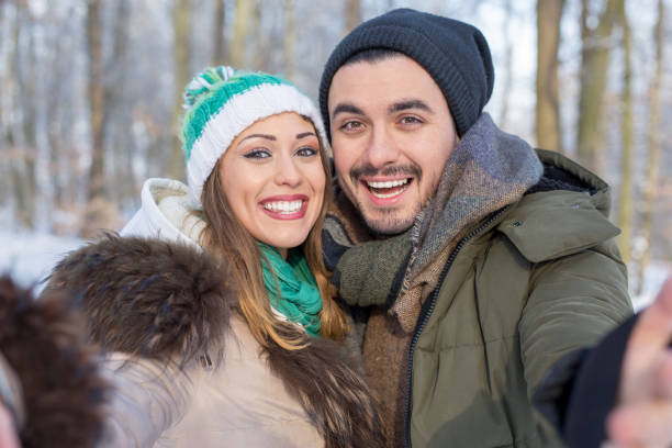 istock Happy smiling couple taking a selfie in a winter forest 1057688136