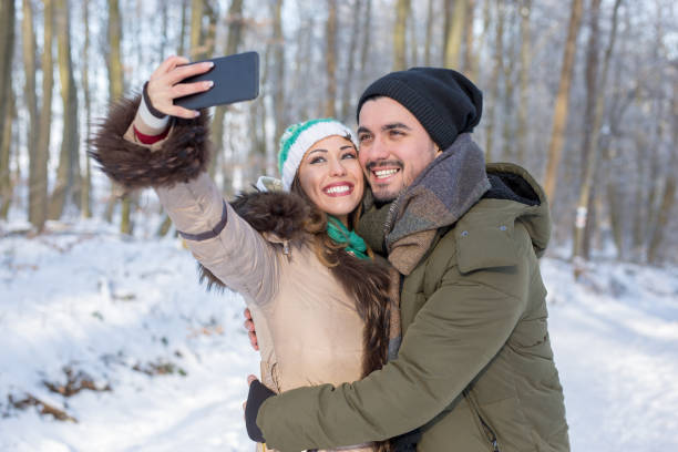 istock Happy smiling couple taking a selfie in a winter forest 1057688158