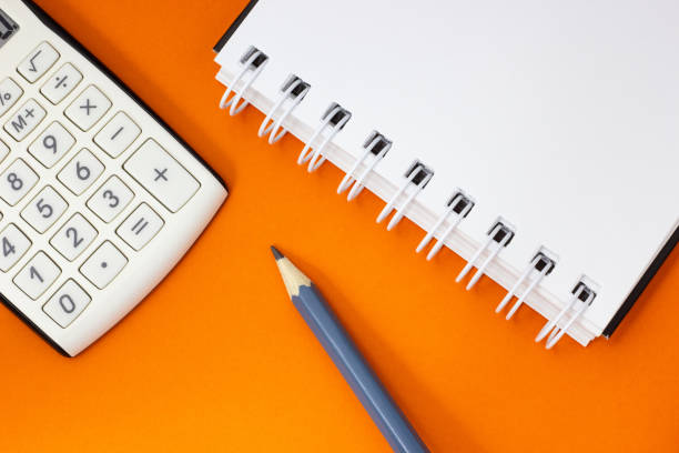 istock Calculator, notebook and pencil on orange background 1057688562