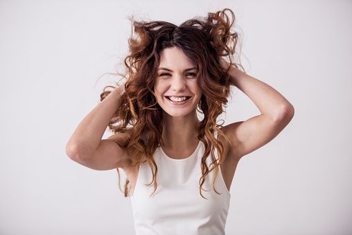 Young pretty girl on a white background playing with her hair. Shooting in the studio.