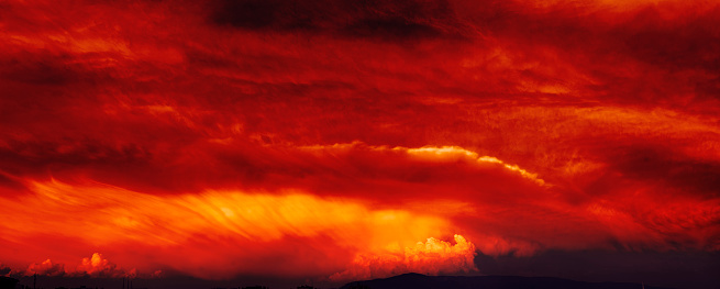 Vibrant colors background photo beauty of a sunset sky ablaze with burning clouds, painted in vibrant hues of red and orange as the evening sun casts its fiery light across the horizon. This abstract background captures the mesmerizing spectacle of nature's canvas, where the sun's rays resemble flames dancing across the sky. Immerse yourself in the breathtaking drama of this sunset scene, a true masterpiece of light and color
