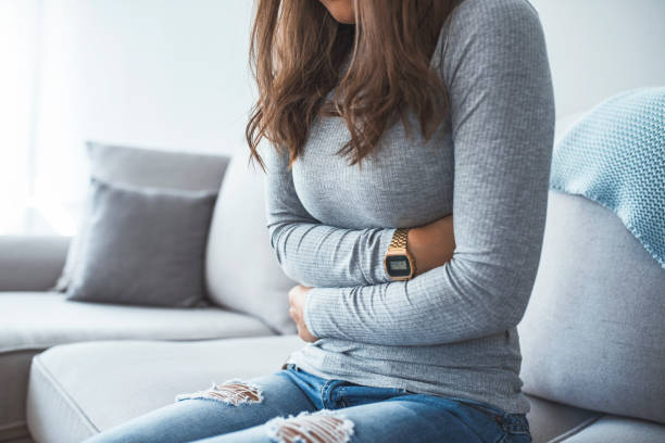 mujer tumbada en el sofá mirando enfermos en la sala de estar - intestino fotografías e imágenes de stock