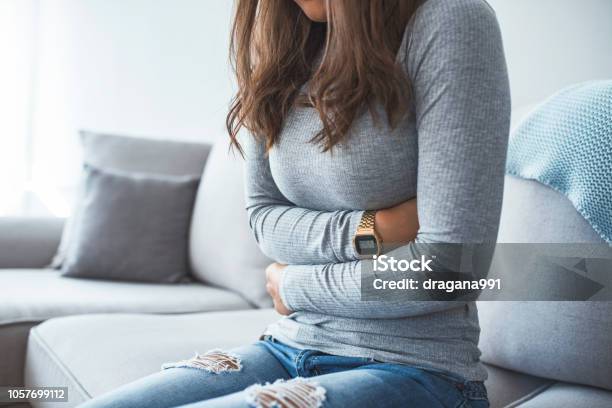 Woman Lying On Sofa Looking Sick In The Living Room Stock Photo - Download Image Now