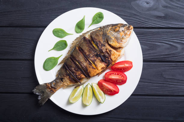 istock Fried fish dorado with lime , tomatoes and spinach 1057702660