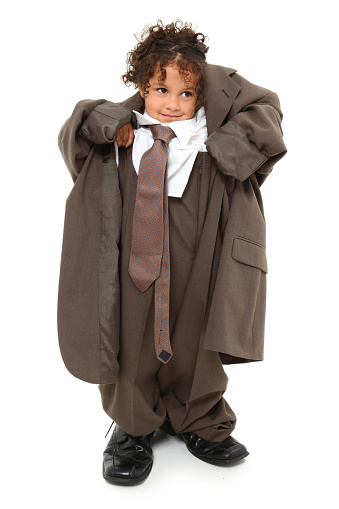 Adorable 3 year old mixed race girl in over-sized baggy suit over white background.