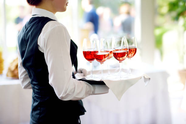 Waitress holding a dish of champagne and wine glasses at festive event Waitress holding a dish of champagne and wine glasses at festive event, party or wedding reception food service occupation food and drink industry party buffet stock pictures, royalty-free photos & images