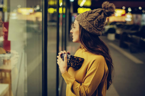 istock woman holding present and looking at store window 1057714562
