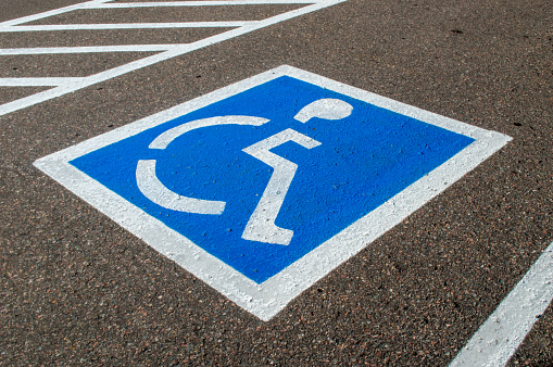 Empty parking spot within a parking lot with handicapped parking symbol on asphalt