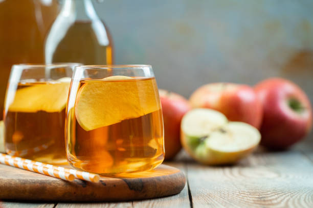 istock Organic Apple cider or juice on a wooden table with copy space. Two glasses with drink and autumn leaves on rustic background 1057728738