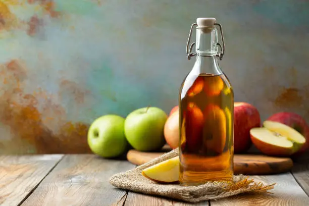 Apple vinegar. Bottle of apple organic vinegar or cider on wooden background. Healthy organic food. With copy space.