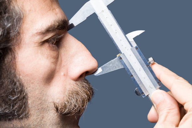 close up portrait of adult man measuring his nose - nose job imagens e fotografias de stock